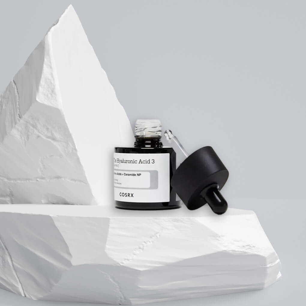 Open bottle of the hyaluronic acid serum sitting on mini iceberg - links to COSRX serum