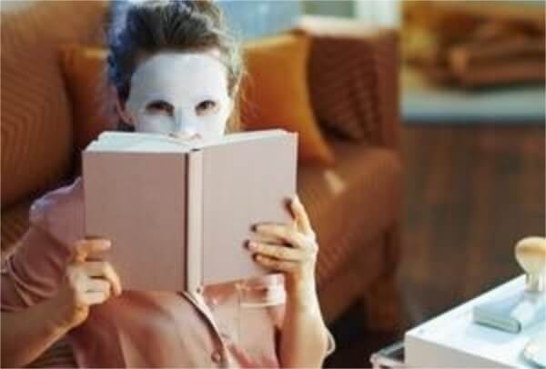 Girl reading a book wearing a korean sheet mask