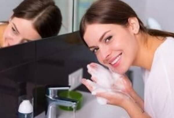 Lady washing face with foamy cleanser